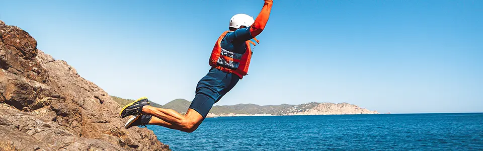 Grupo de aventureros saltando desde acantilados durante una experiencia de coasteering en Ibiza