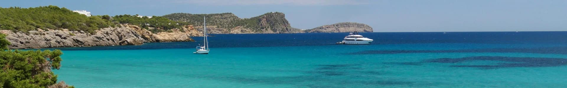Panoramic view of Ibiza's dramatic limestone cliffs and turquoise Mediterranean waters along the coasteering route.